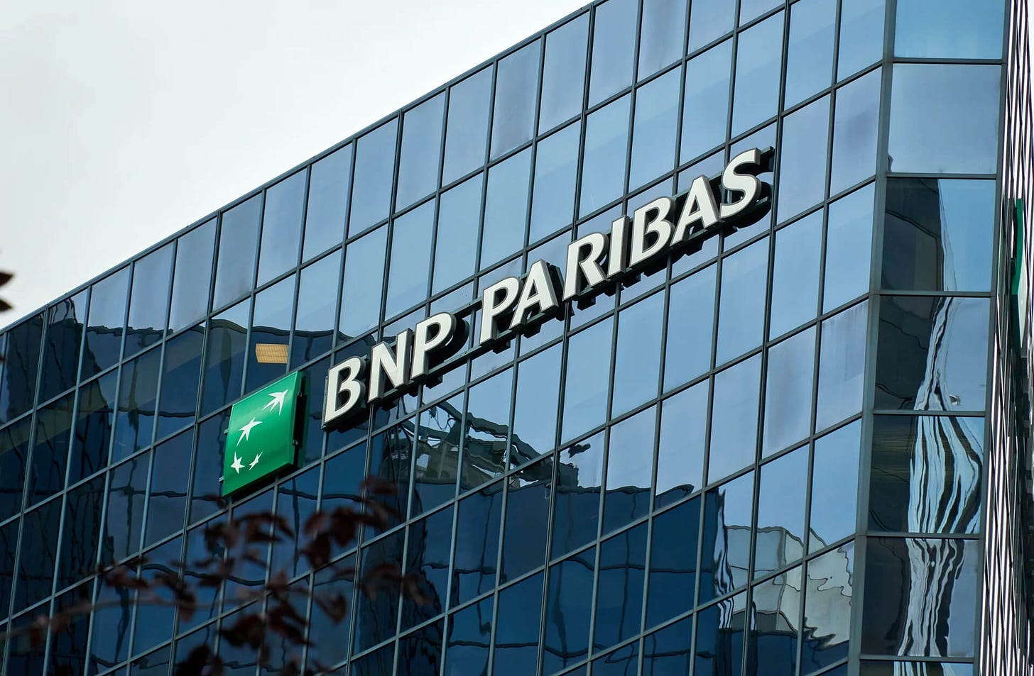 Vista exterior de prédio do banco BNP Paribas com vidro espelhado e logo da empresa.