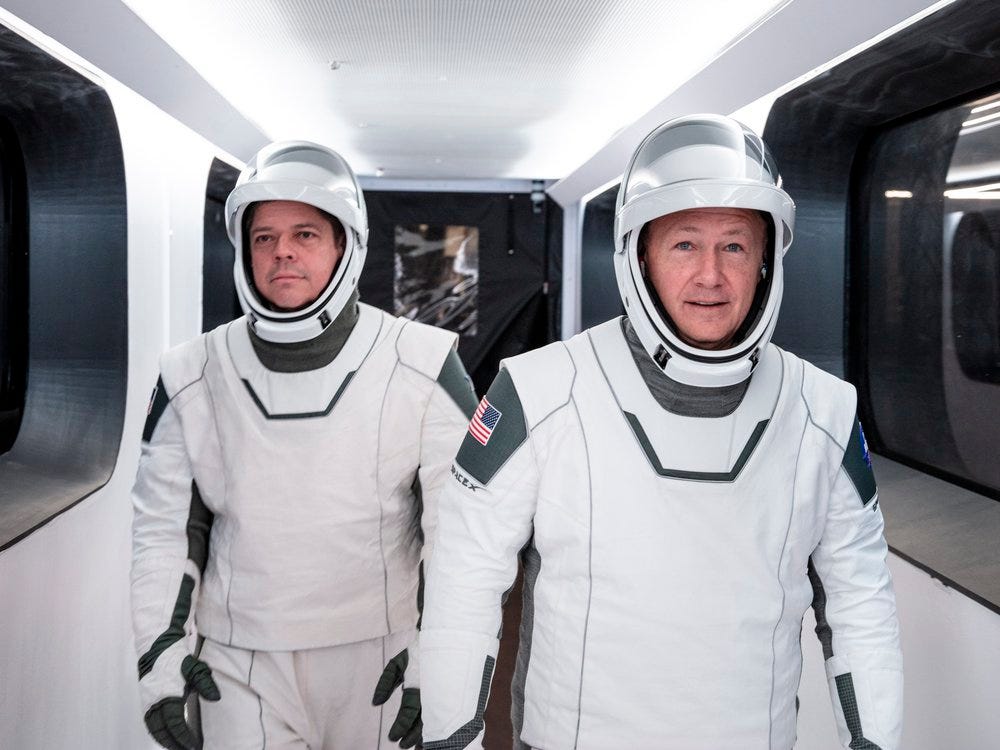 Astronauts Bob Behnken and Doug Hurley walk through Crew Access Arm in SpaceX spacesuits during a dress rehearsal for the first crewed SpaceX launch.