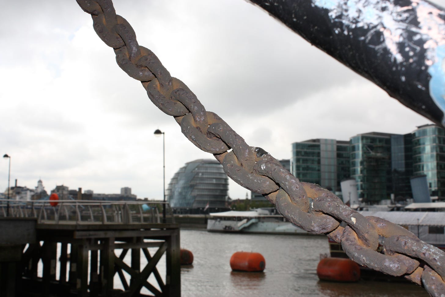 photo of a rusty chain on a pier on the edge of an urban river