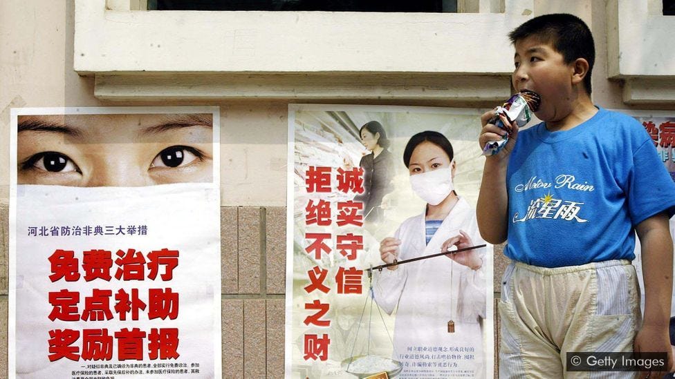 In front of posters about the Sars epidemic, a boy eats ice cream, which we collectively spend more on than preventing extinction through our technology (Credit: Getty Images)