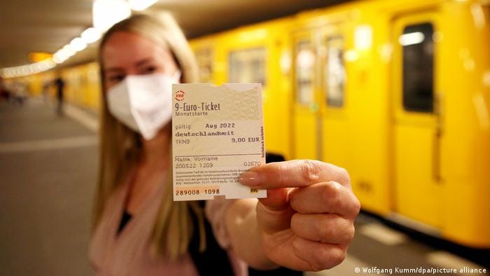 A woman on a train platform holds up the €9 ticket, which allows travel on all local and regional transport in Germany for just €9 a month. 