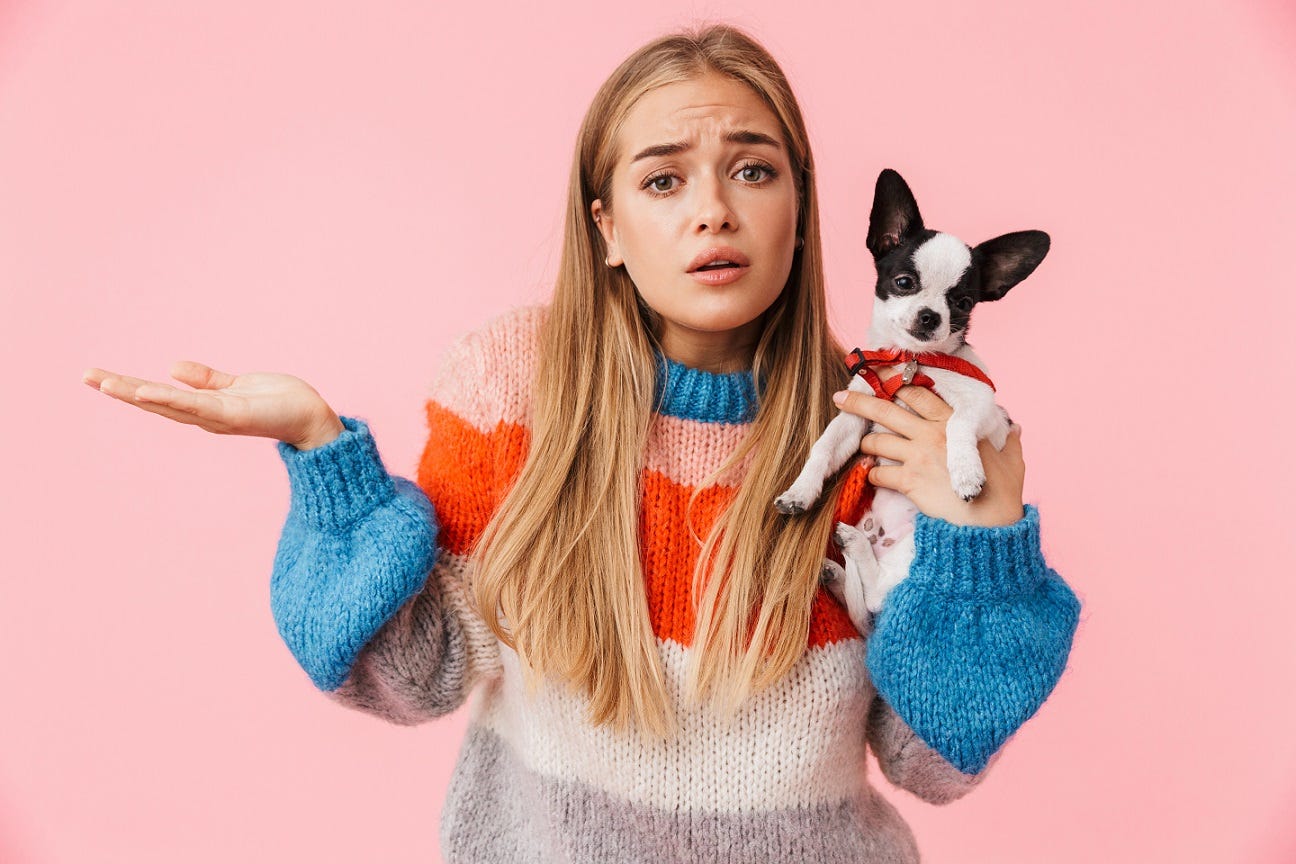 A woman holding a dog looking confused