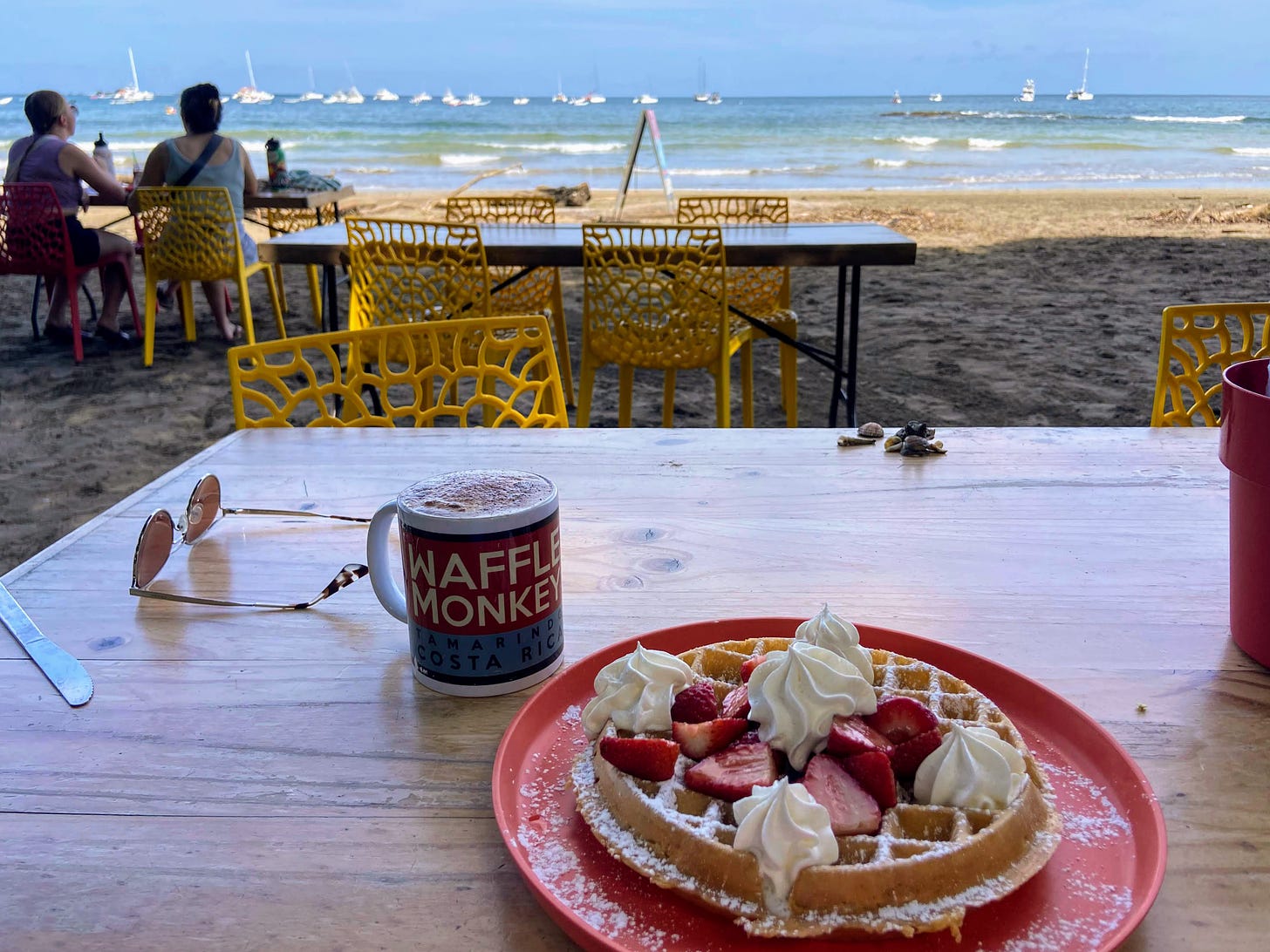 A waffle on a table overlooking the beach and sea.