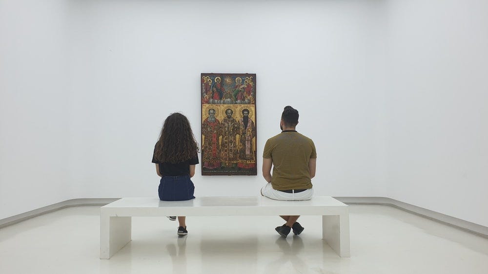two persons sitting near each other and looking at artwork