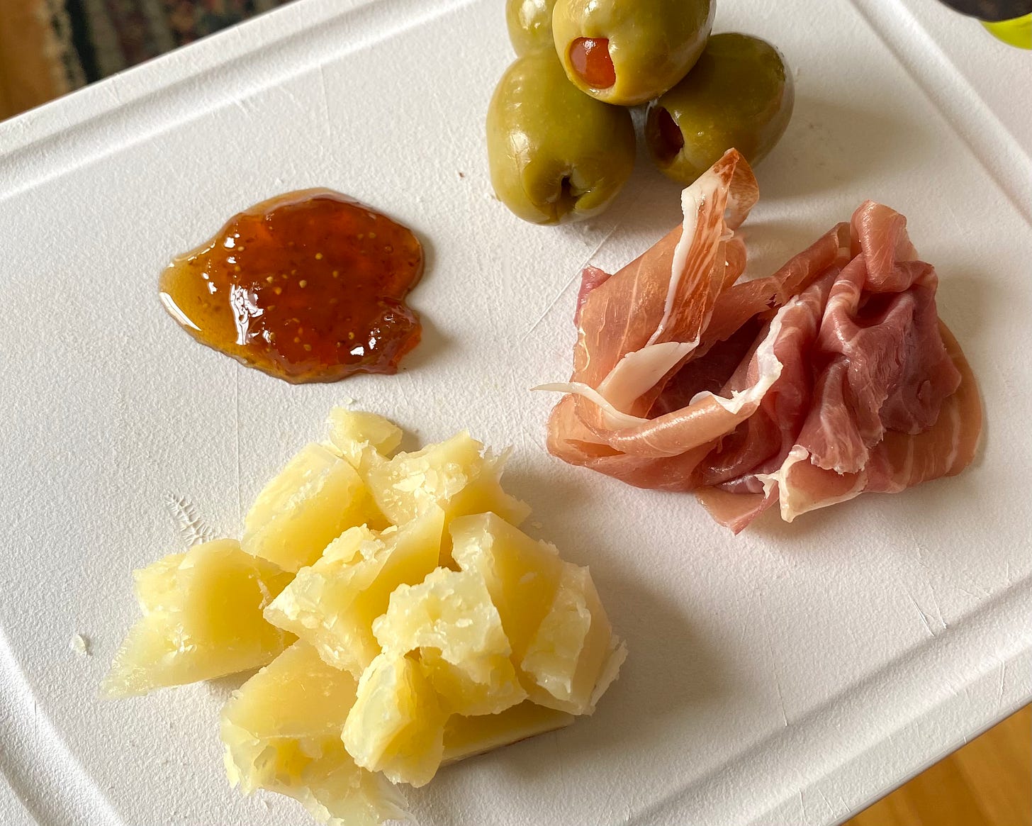 cheese plate with aged manchego chunks, prosciutto, spanish olives, fig spread