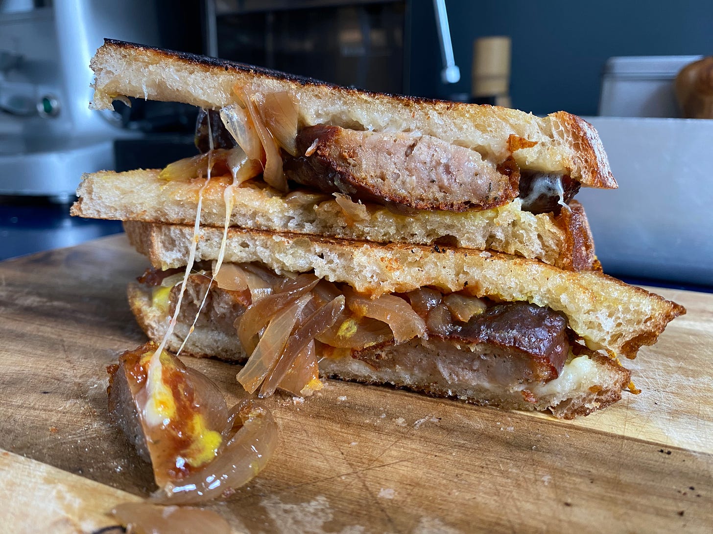 Sausage, onion and mustard sandwich on a wooden chopping board