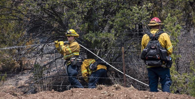 Jeff Franco, left, and other wildland firefighters from Apple Valley, Calif., mop up hot spots along NM 283 near Las Vegas, N.M., Thursday, May 5, 2022. Firefighters are trying to hold the Calf Canyon/Hermit Peak Fire at the road and not let it cross. (Eddie Moore/The Albuquerque Journal via AP)
