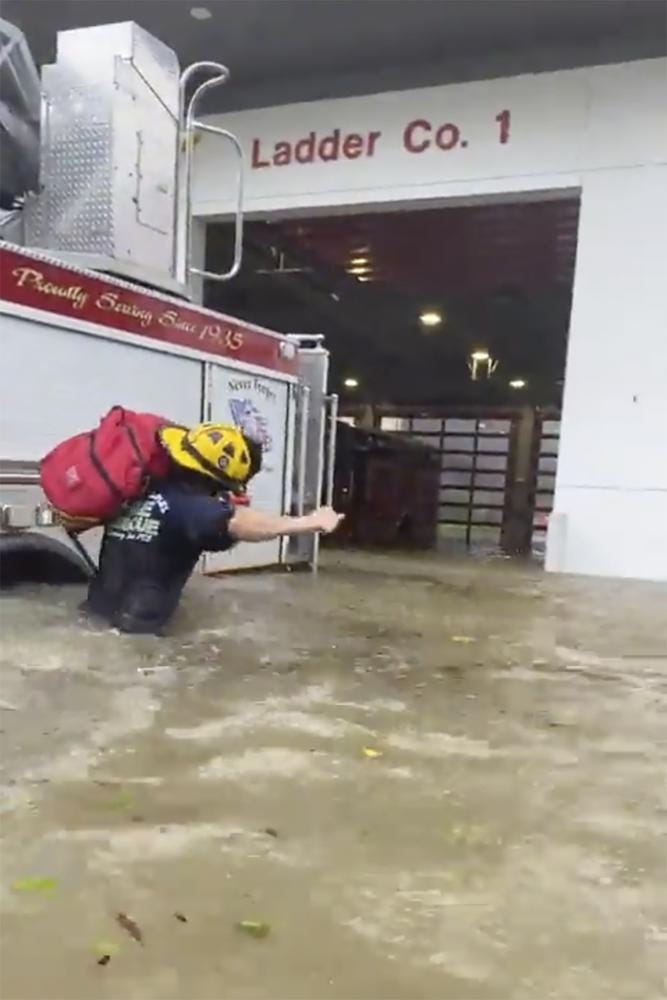 This image provided by the Naples Fire Rescue Department shows a firefighter carrying gear in water from the storm surge from Hurricane Ian on Wednesday, Sept. 28, 2022 in Naples, Fla.  Hurricane Ian has made landfall in southwestern Florida as a massive Category 4 storm.  (Naples Fire Department via AP)