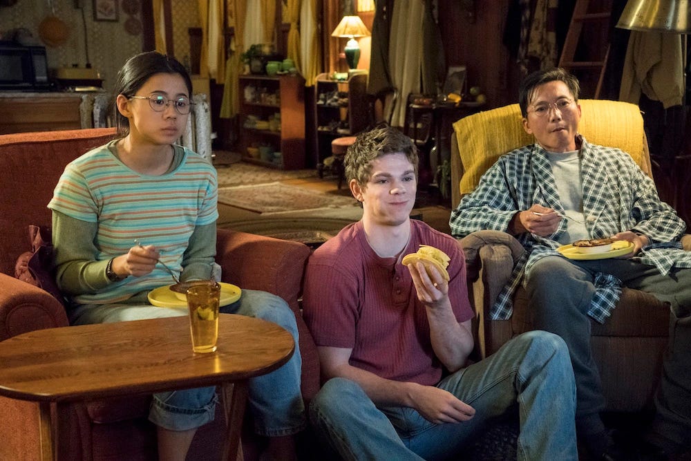 Leah Lewis as Ellie, Daniel Diemer as Paul and Collin Chou as Ellie's dad, all watching tv and eating together in the living room.