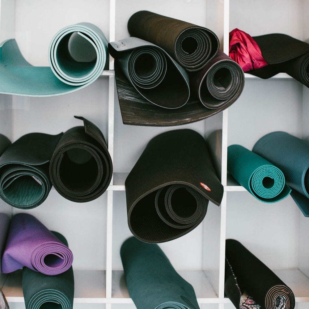 black, blue and purple yoga mats on white shelf