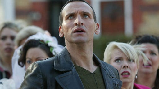 This image from "Father's Day" (Doctor Who Season 1's eighth episode) sees the Ninth Doctor (played by Christopher Eccleston) shielding a wedding party from the off-screen Reapers. The Doctor's concerned expression contrasts the fear on the faces of the other people in view. This image from "Father's Day" (Doctor Who Season 1's eighth episode) sees the Ninth Doctor (played by Christopher Eccleston) shielding a wedding party from the off-screen Reapers. The Doctor's concerned expression contrasts the fear on the faces of the other people in view.