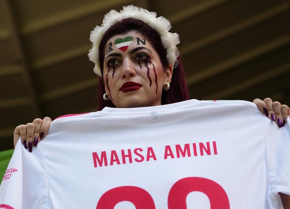 A woman holds a jersey with the name of Mahsa Amini, a woman who died while in police custody in Iran at the age of 22, as she takes her place in the stands ahead of the World Cup group B soccer match between Wales and Iran, at the Ahmad Bin Ali Stadium in Al Rayyan, Qatar, Friday, Nov. 25, 2022. (AP Photo/Pavel Golovkin)