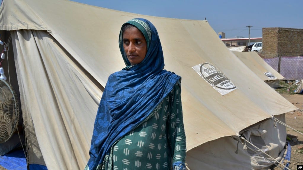 Shakeela Bibi who is pregnant stands beside her tent at a relief camp for flood victims, in Fazilpur near Multan, Pakistan, Sept. 23, 2022.