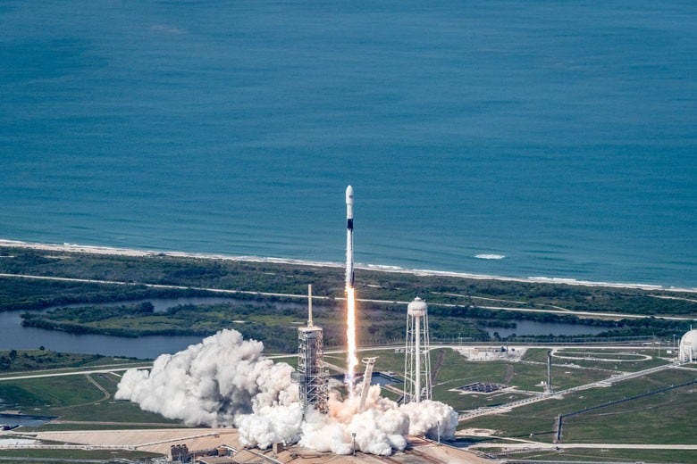 a rocket launching with the bright blue ocean in the background