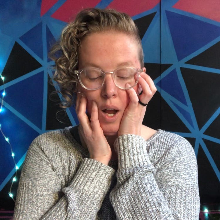 a person in front of a geometric background with hands pressing into their cheeks, speaking