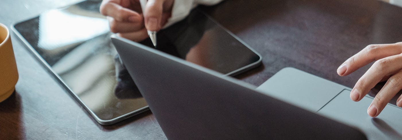 Someone on a desktop with an iPad and a MacBook Pro