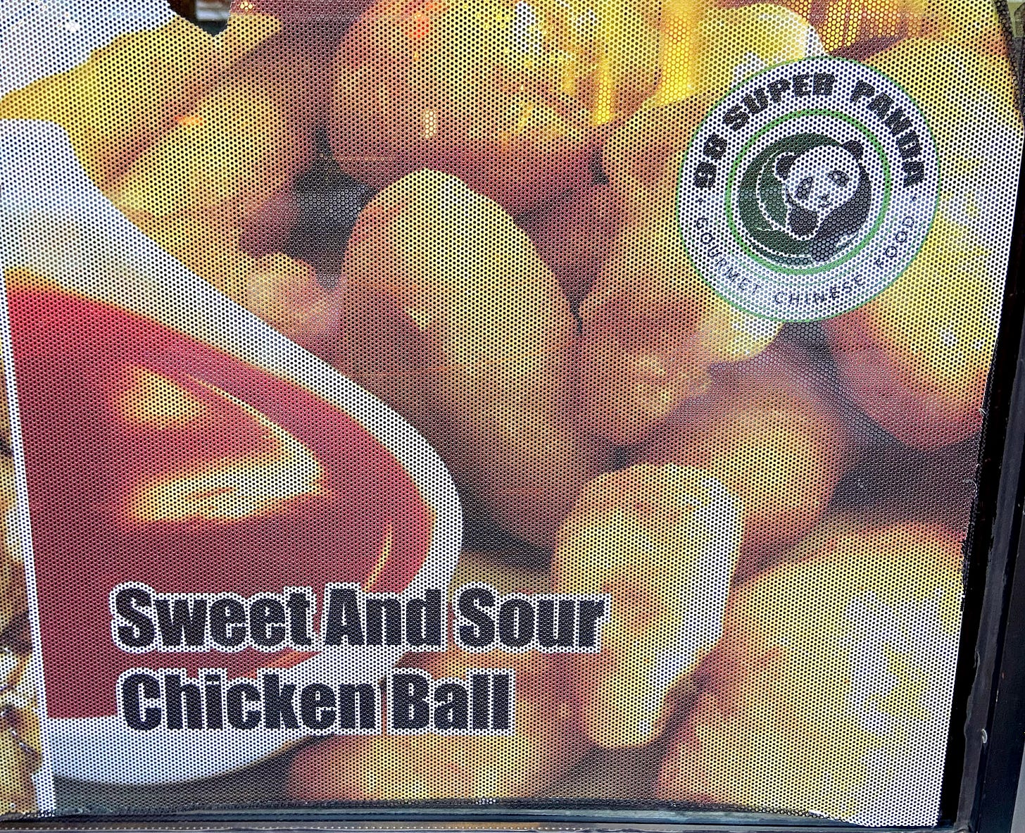 Window sign advertising sweet and sour chicken balls, with photo of chicken balls