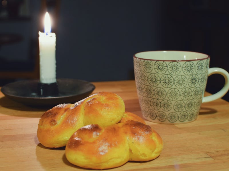 saffron buns, coffee cup, and lighted candle