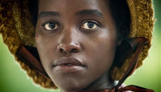 This image shows Patsey (played by Lupita Nyong'o) wearing a bonnet and looking at something just out of camera range.