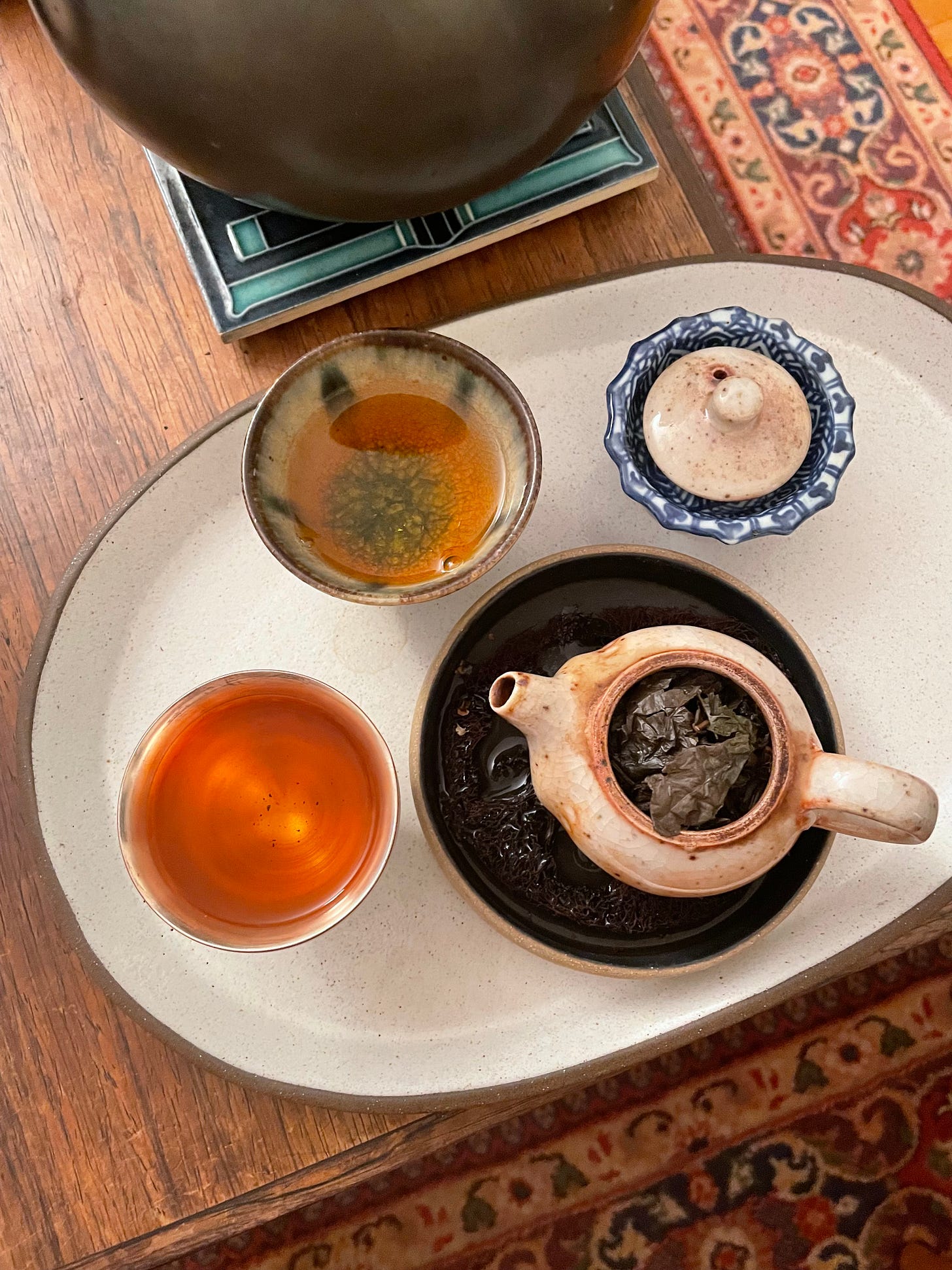 ID: Photo of a ceramic tray holding a small teapot and two ceramic cups