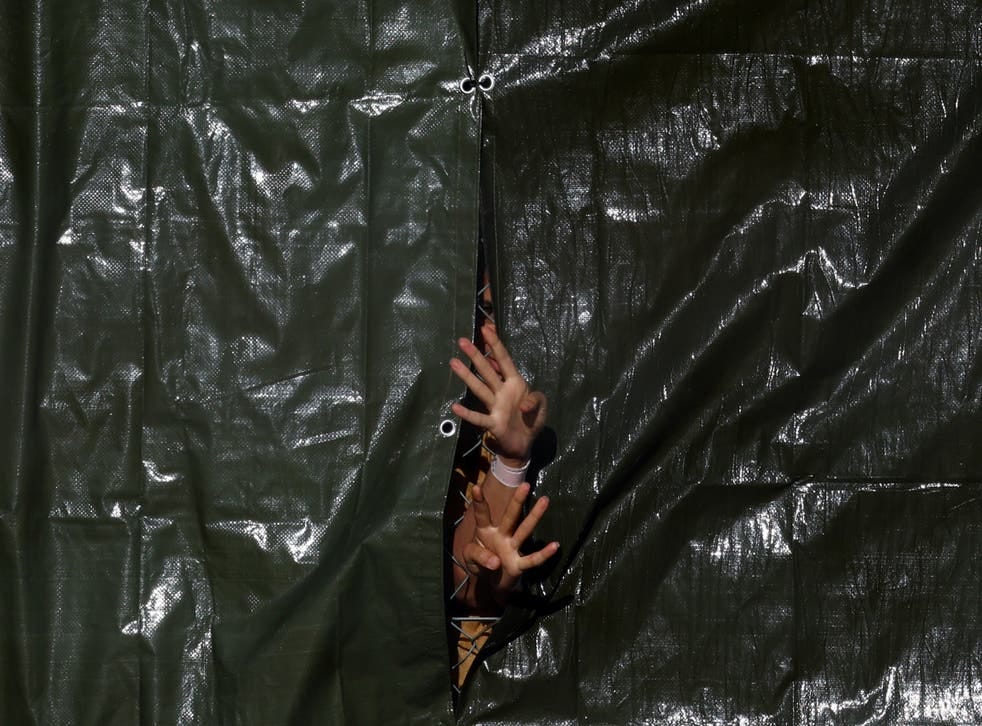 <p>Detainees gesture through a fence at an immigration processing centre in Manston</p>