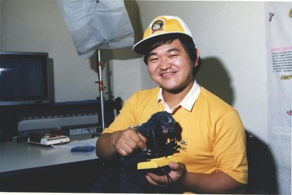 A photo of Takahashi Meijin holding a joystick, wearing a hat as he so often was seen doing