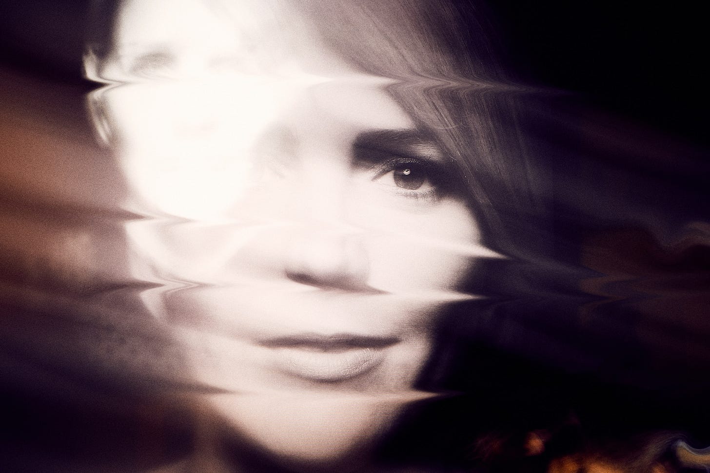 A woman's face in close-up that has been blurred a little and distorted by horizontal skew lines.