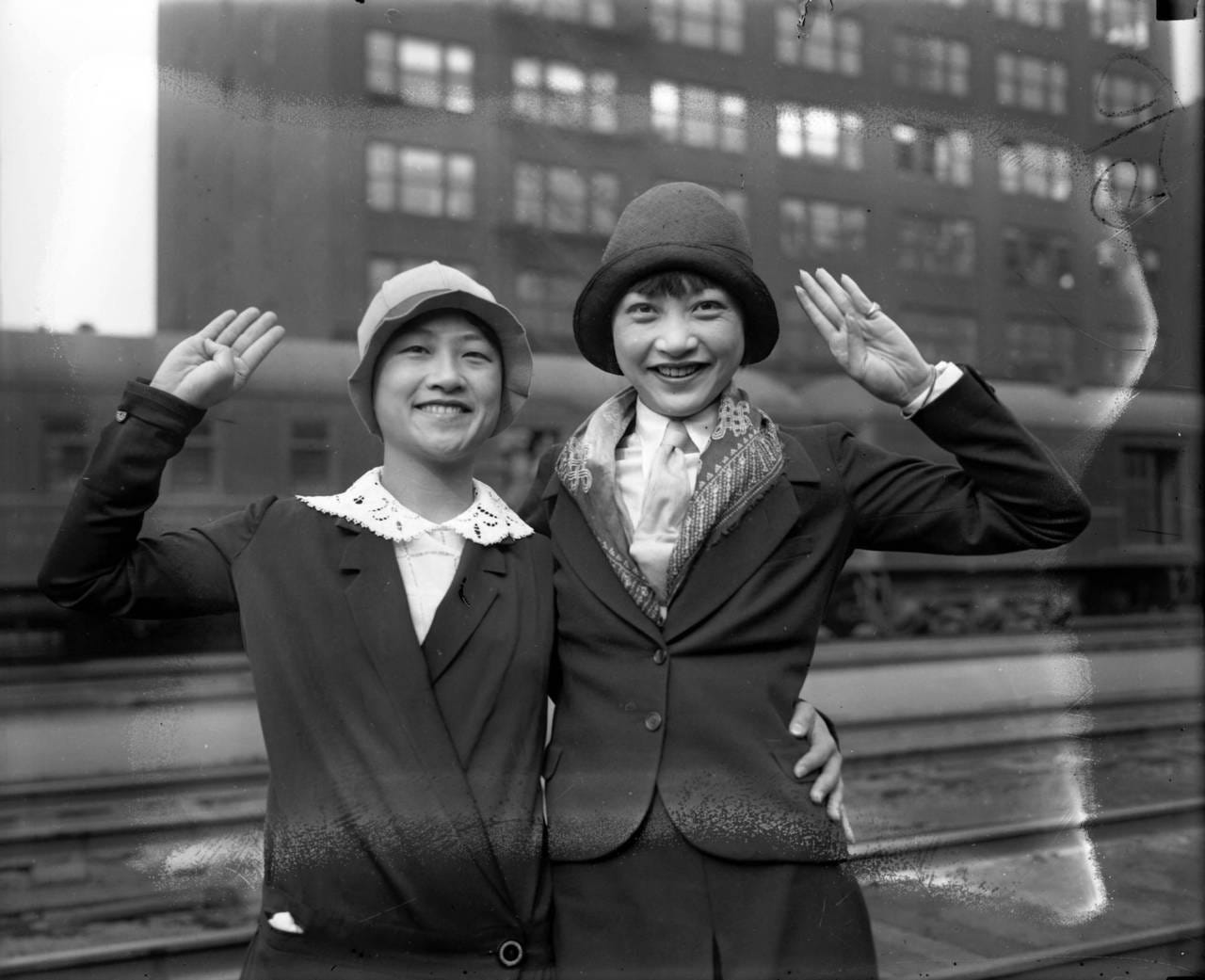 black and white photo of Lulu and Anna May posing with their hands in salute in a train yard in Berlin, 1928