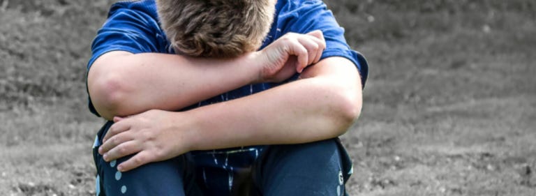 child sitting alone head bowed