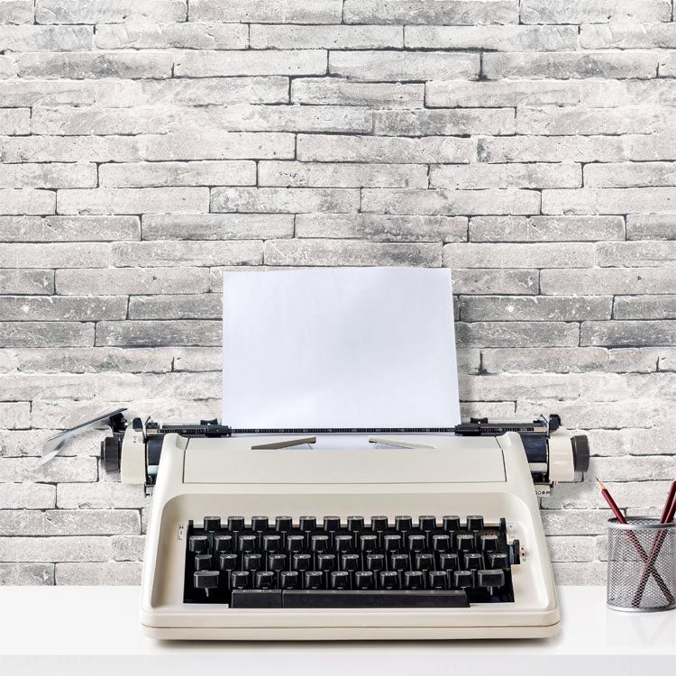 Typewriter with blank page and brick wall representing writer's block.