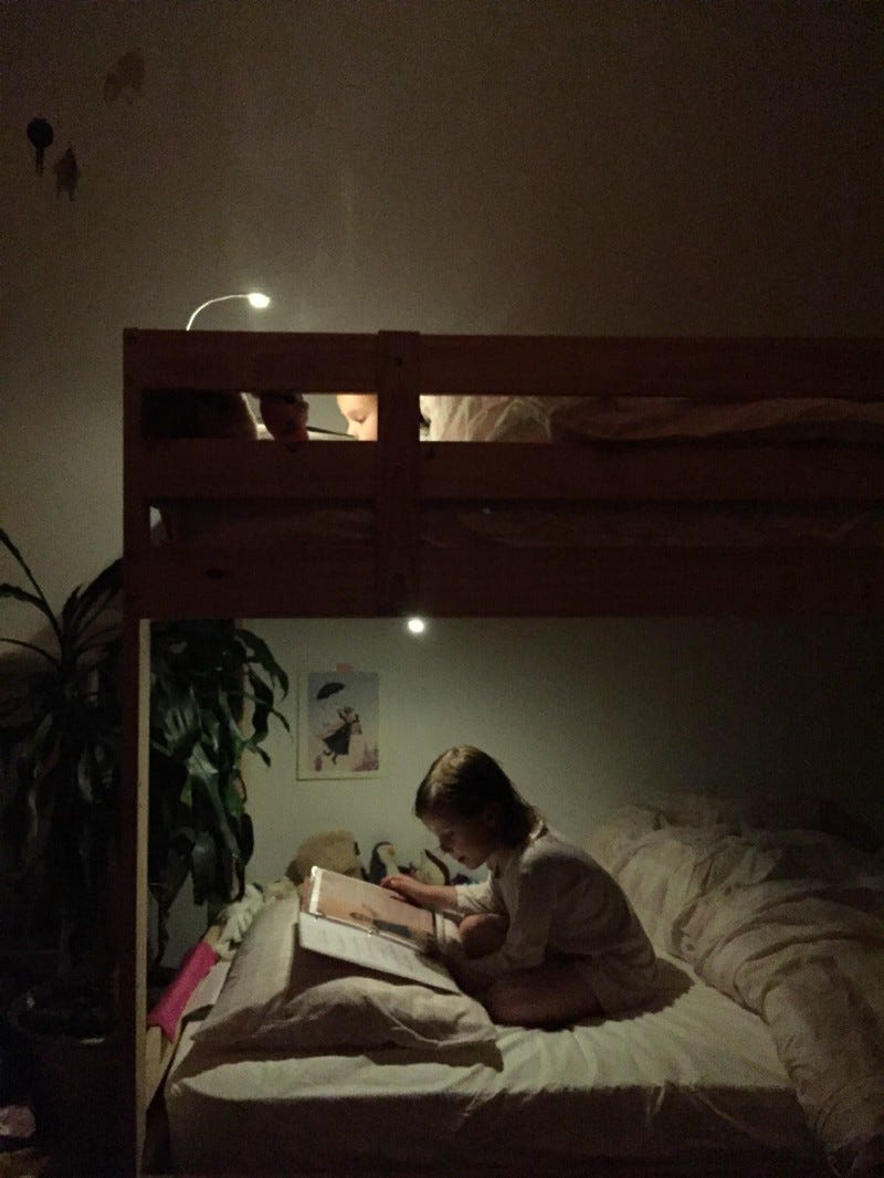 two girls read while laying down in bunkbeds