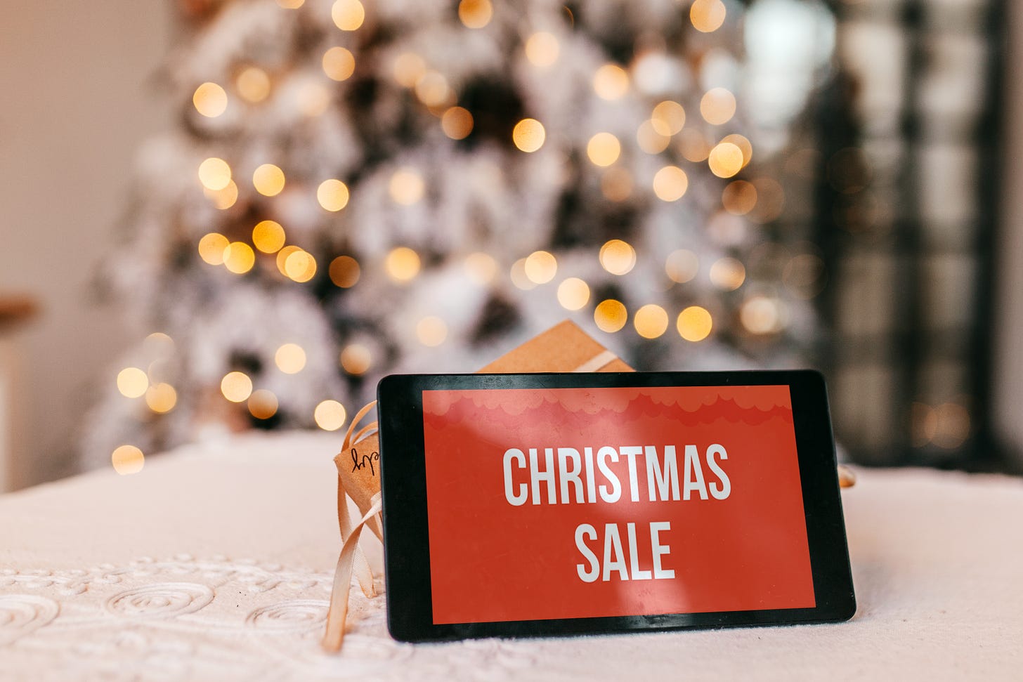 A phone bearing text that reads "Christmas Sale" stands against a traditional holiday background.