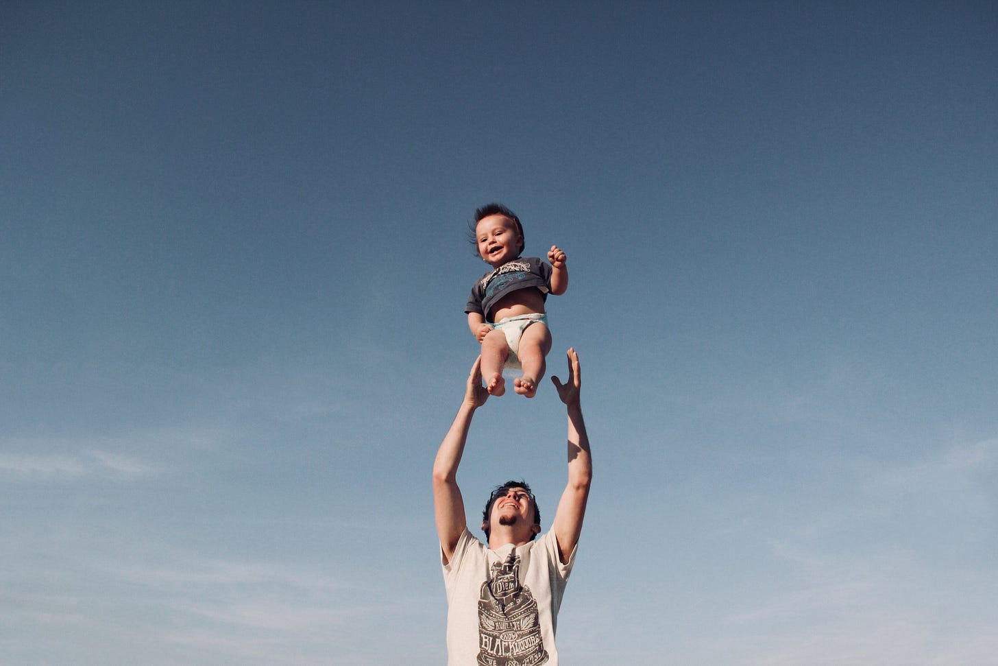Фотография мужчины, воспитывающего ребенка под голубым небом