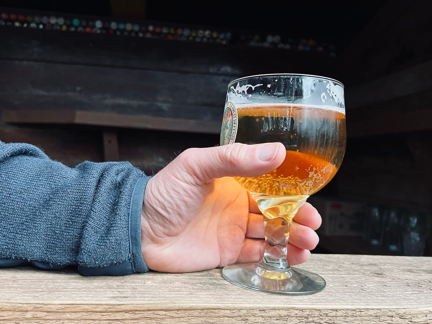 A glass of light ale is held in a hand