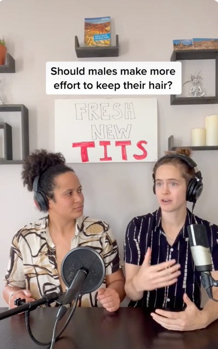 two women sit at a table with sign that reads fresh new tits