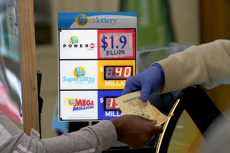 A customer is handed Powerball tickets purchased at Lichine's Liquor & Deli in Sacramento, Calif., Monday, Nov. 7, 2022. Monday night's drawing is  estimated to be a record $1.9 billion. (AP Photo/Rich Pedroncelli)