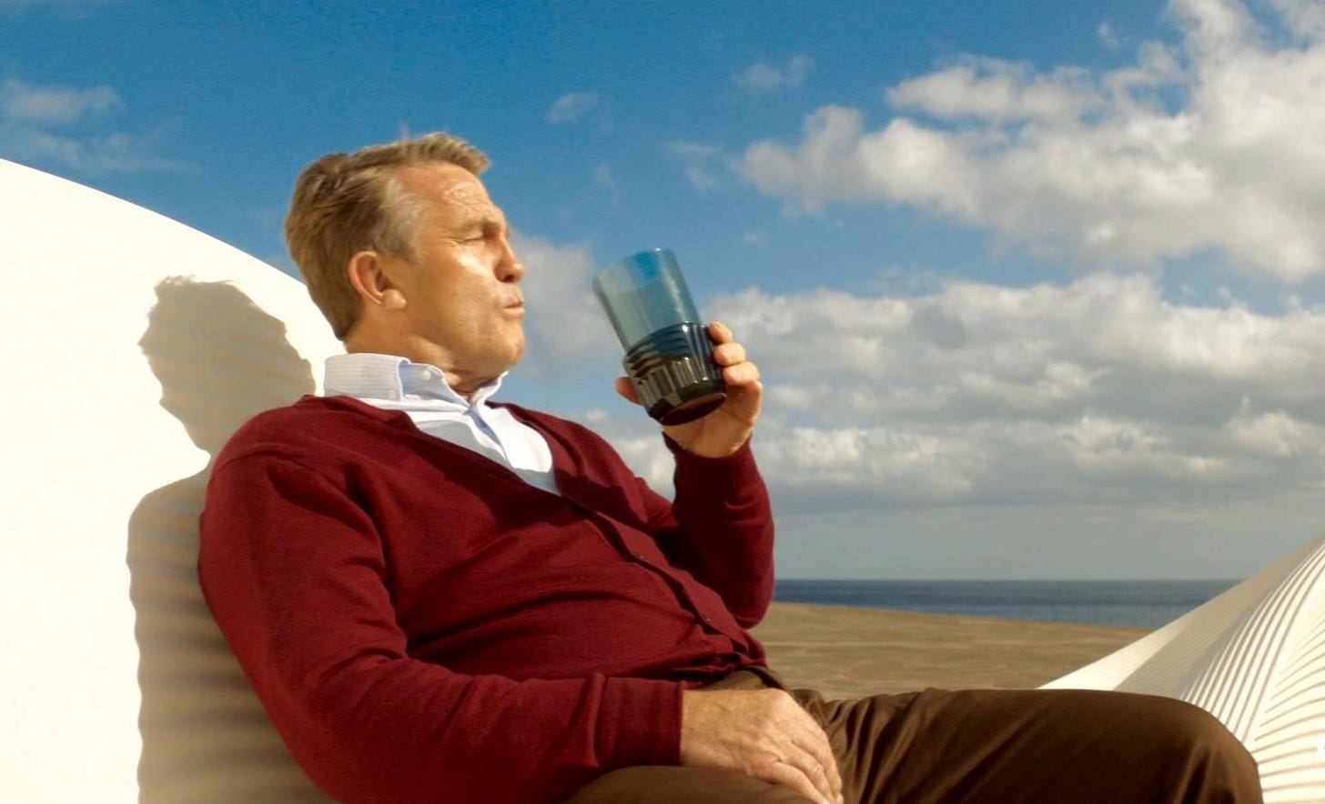 This image shows Graham O'Brien (played by Bradley Walsh) reclining in a posh lounge chair and holding a drink glass (from which he's just sipped) at Tranquility Spa. A beach, the ocean, and a beautiful, cloud-filled sky are visible behind him. This image shows Graham O'Brien (played by Bradley Walsh) reclining in a posh lounge chair and holding a drink glass (from which he's just sipped) at Tranquility Spa. A beach, the ocean, and a beautiful, cloud-filled sky are visible behind him.