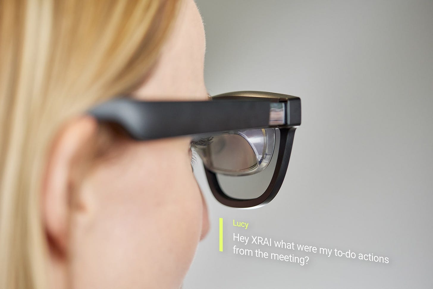 Closeup view of person wearing XRAI glasses with text captions overlay below glasses