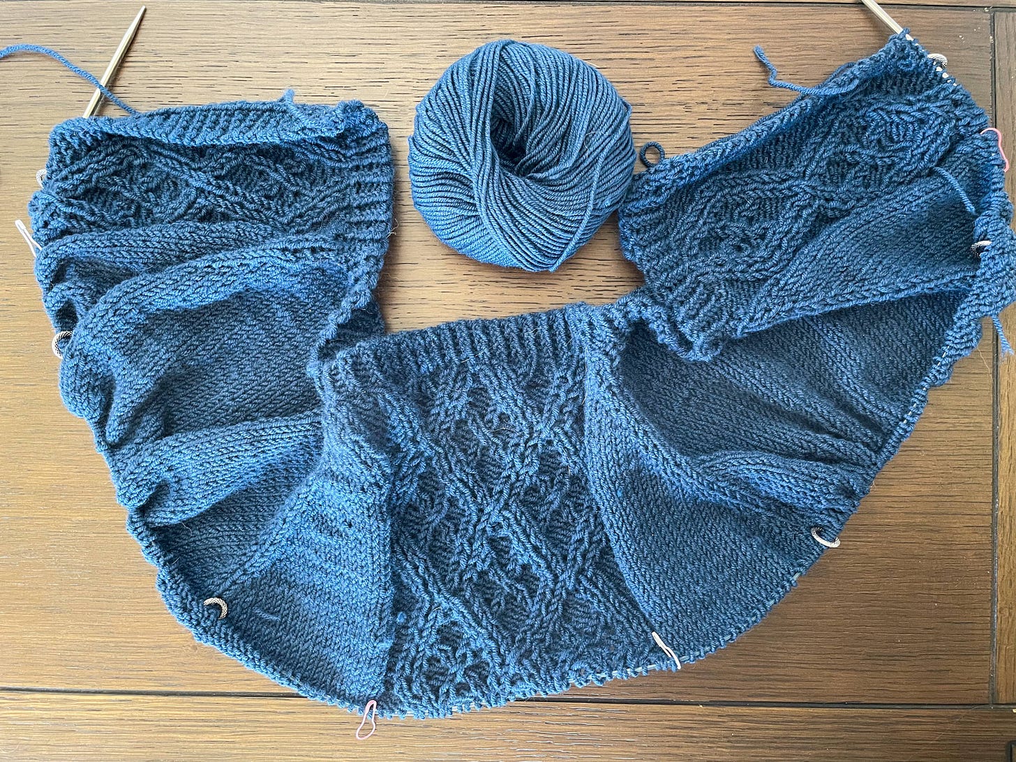 A sweater in progress, with three cable panels. 