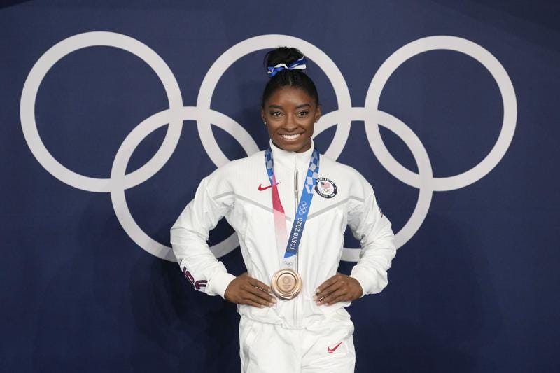FILE - Simone Biles, of the United States, poses wearing her bronze medal from balance beam competition during artistic gymnastics at the 2020 Summer Olympics, Aug. 3, 2021, in Tokyo, Japan.  President Joe Biden will present the nation’s highest civilian honor, the Presidential Medal of Freedom, to 17 people, at the White House next week. (AP Photo/Natacha Pisarenko, File)