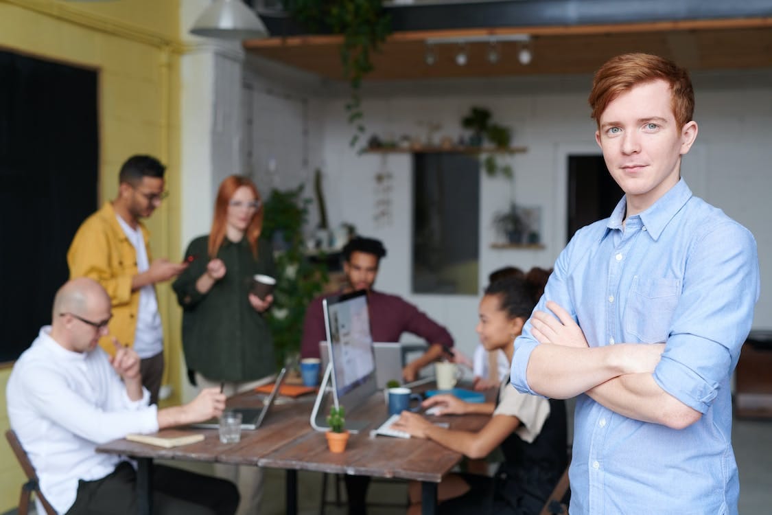 Free Man Standing Beside People Sitting Beside Table With Laptops Stock Photo