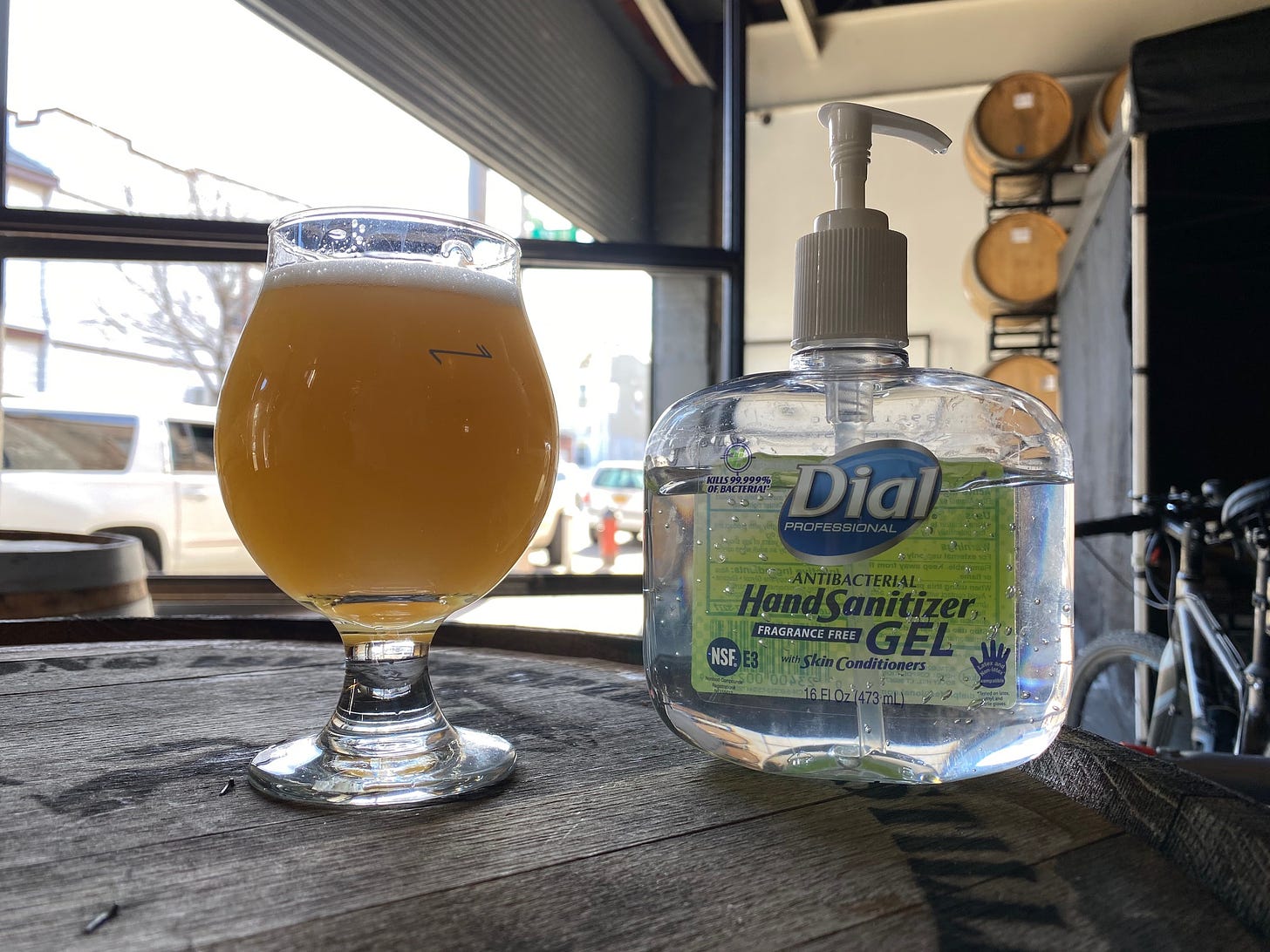 A glass of hazy IPA next to a bottle of hand sanitizer