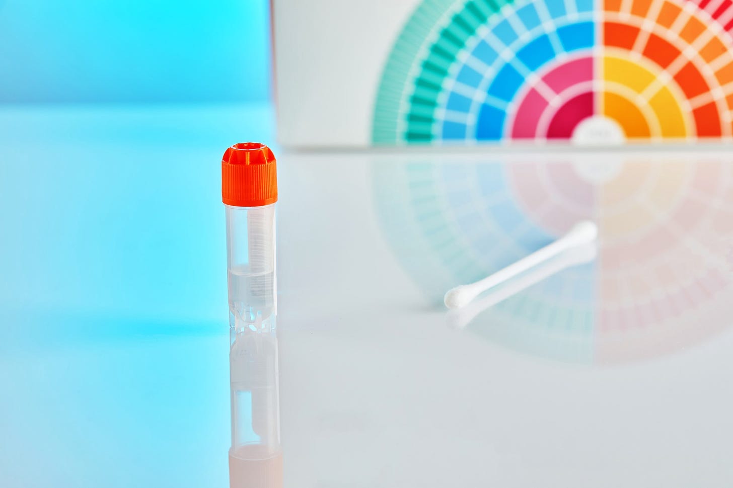 A test tube and swab stand against the background of a testing kit.