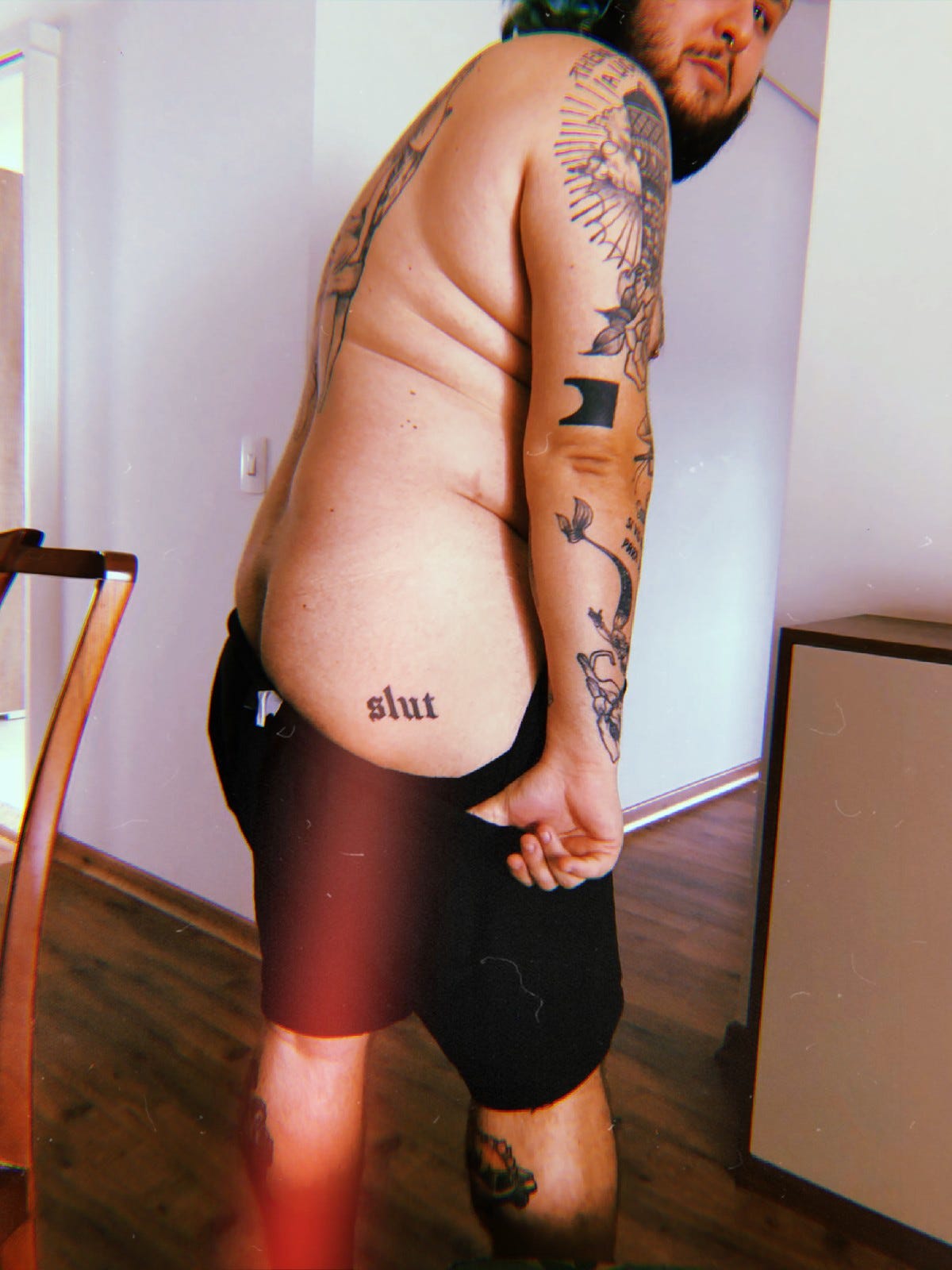 Photo of me holding my shorts down to show the word "slut" tattooed on my butt