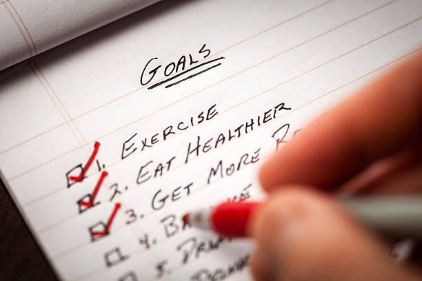 Hand Holding Red Marking Pen Checking Off List of Goals Closeup showing a hand checking off goals that were accomplished. fitness goals stock pictures, royalty-free photos & images