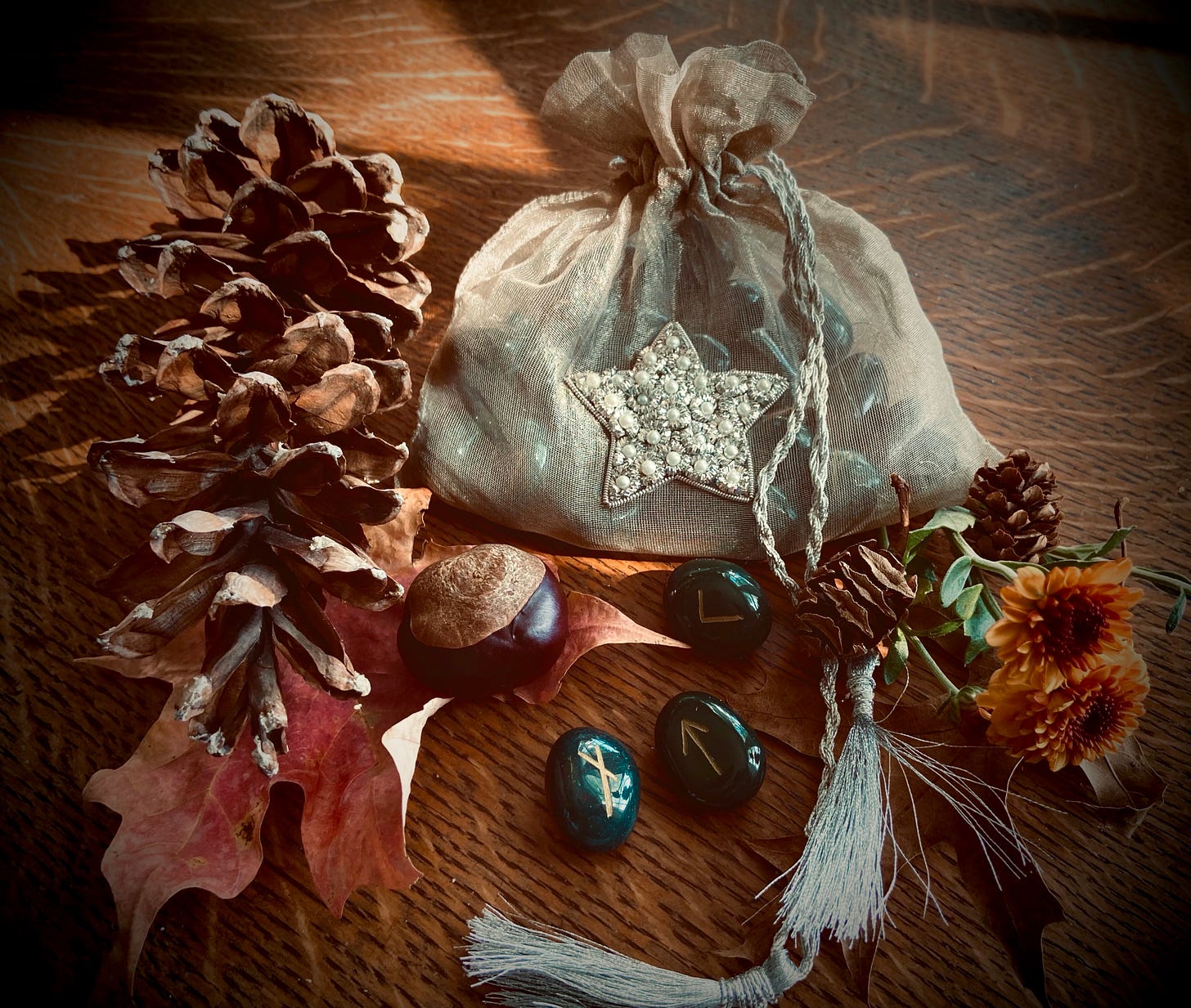 Rune stones and star bag amid autumn leaves and mums