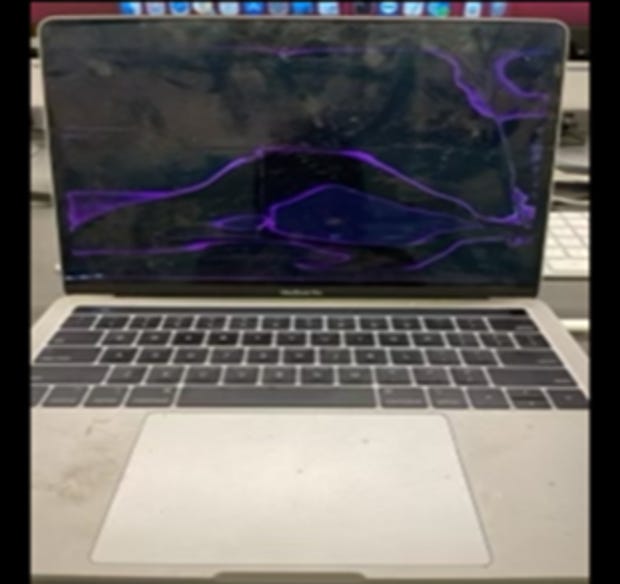 Blurry photograph of a Macbook Pro with a possibly broken screen and dirt on the keyboard area
