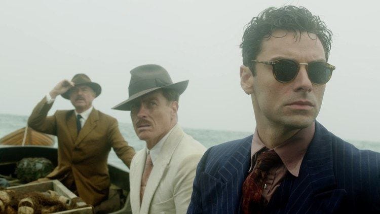 Three men in the AND THEN THERE WERE NONE miniseries on a boat look off-camera with an empty gray horizon stretching behind them 