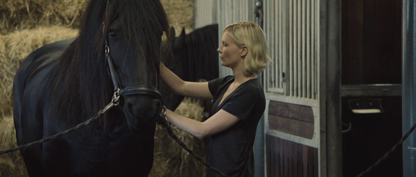 Film still from Melancholia. Justine touches a horse in a stable.