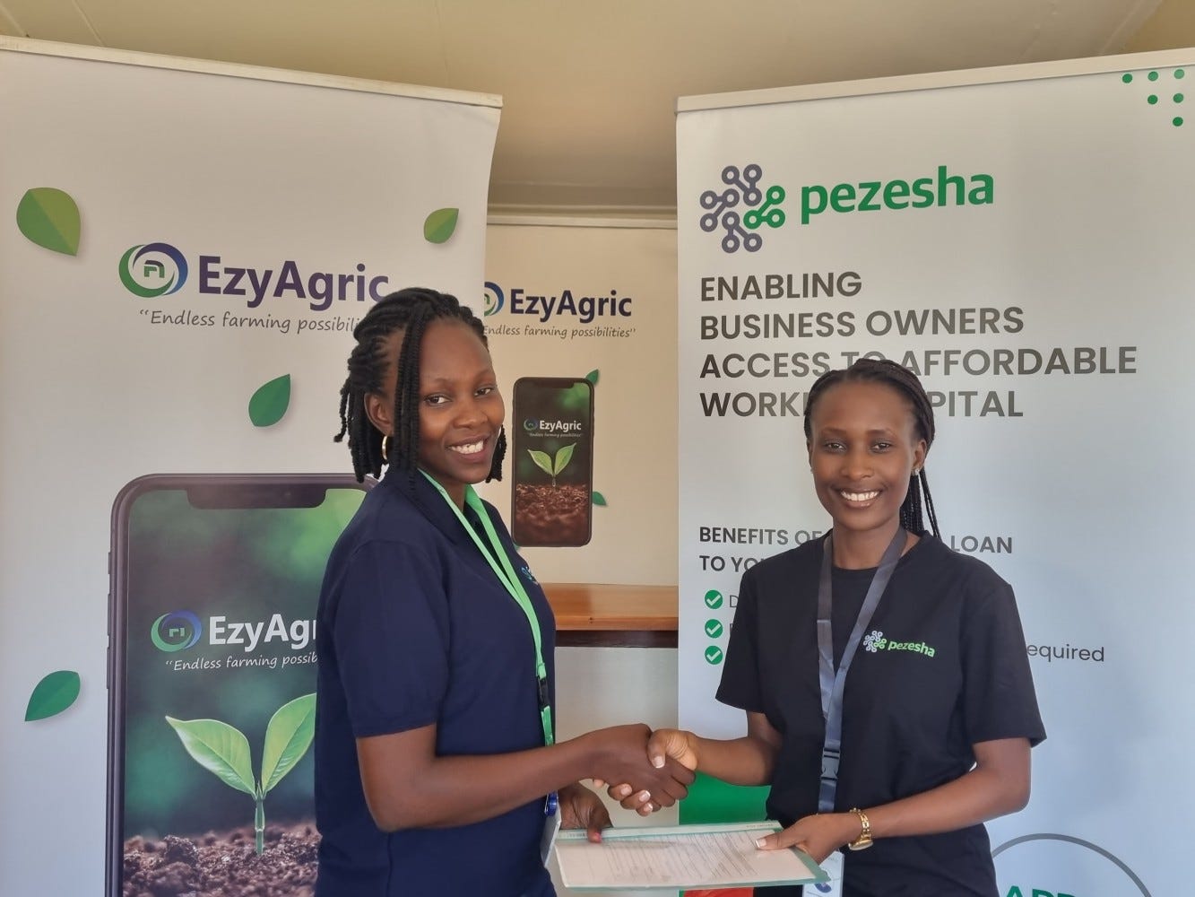 Zilla Mary Arach, Chief Product Officer at EzyAgric shaking hands with Jessica Tusiime, the Uganda Country Manager of Pezesha